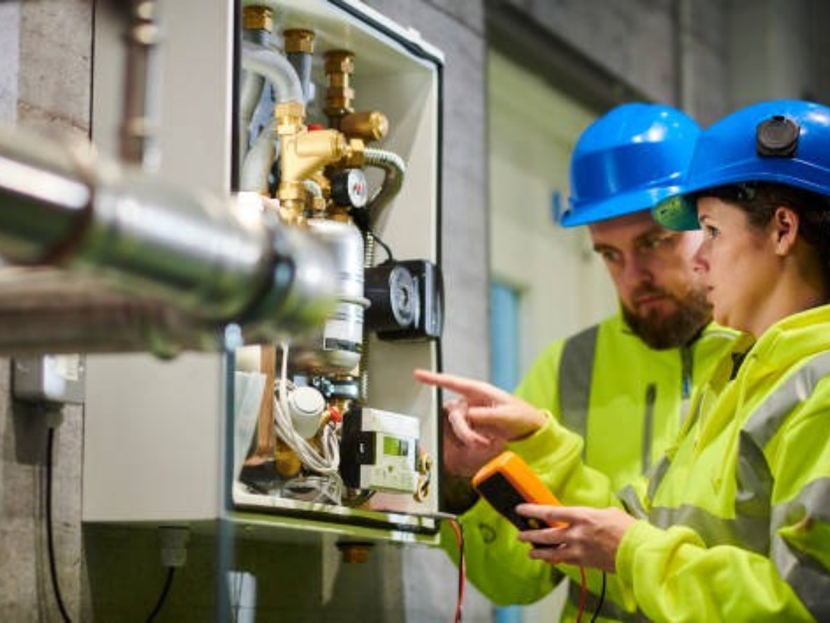 Technicians testing an electrical and plumbing control panel