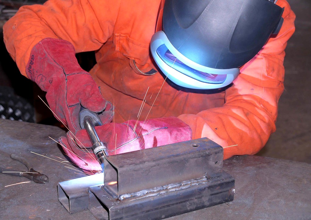 Welder in protective gear performing a weld test