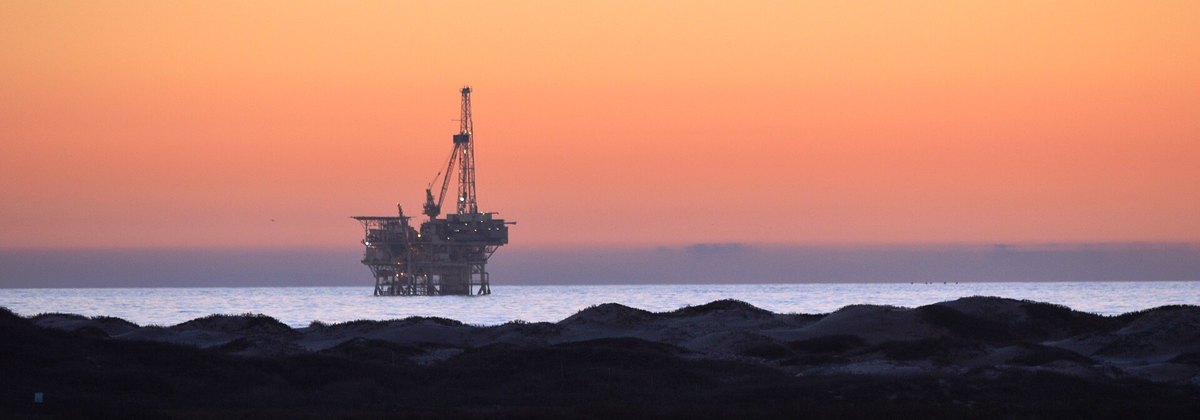 Offshore oil platform on the horizon at dusk